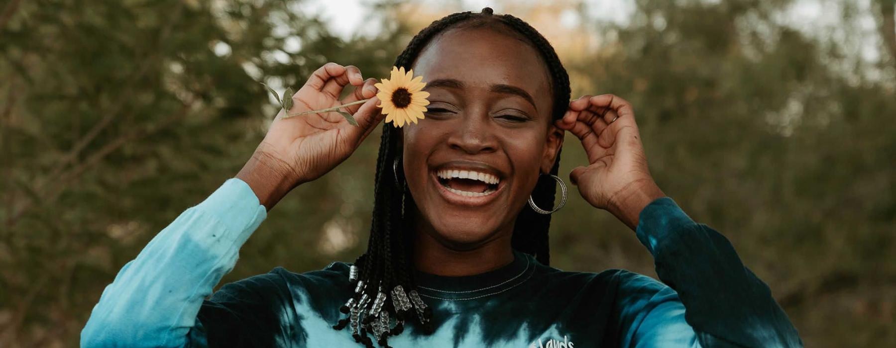 woman holds a flower in her hair in a park