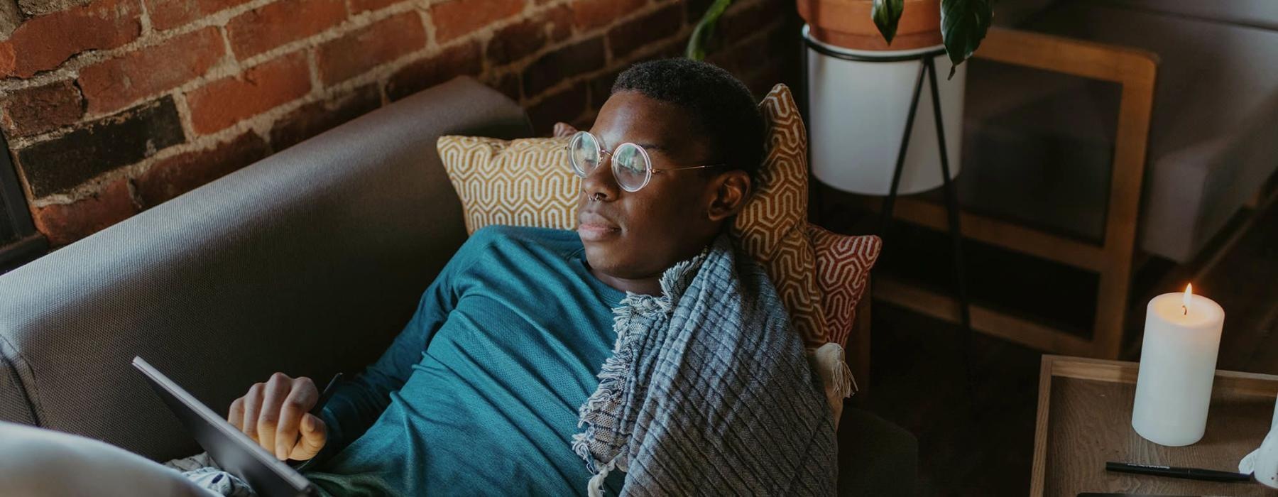 a man looks at his tablet while lying on his living room couch